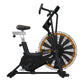 Black and gold stationary exercise bike with large fan wheel, padded seat, and drop handlebars on white background