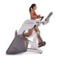 Woman in red sports bra using gray and charcoal Octane Fitness ZR7000 Zero Runner exercise machine on white background