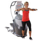 Woman wearing red tank top and black capri leggings exercising on gray and white Octane Q35x elliptical machine