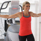 Woman wearing red tank top and black pants with arm weights, smiling with arms outstretched next to Octane Q47x elliptical ma