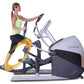 Woman wearing lime green tank top and black pants using gray and black Octane XT-One elliptical with yellow accent on pedals