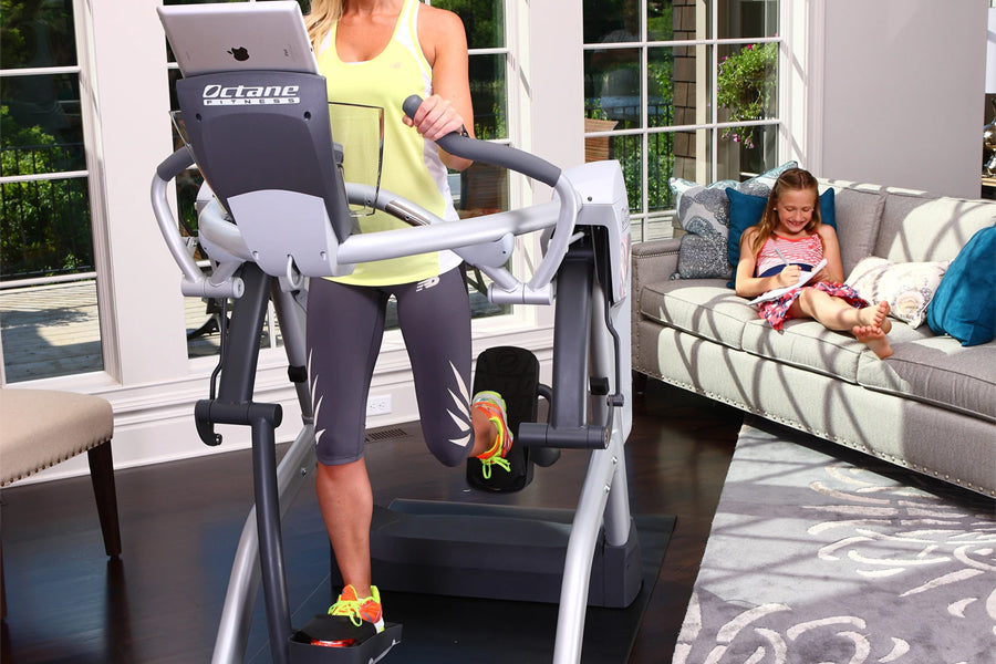 Woman in yellow tank top using Octane Fitness ZR7 Zero Runner treadmill with gray and white frame in home gym setting