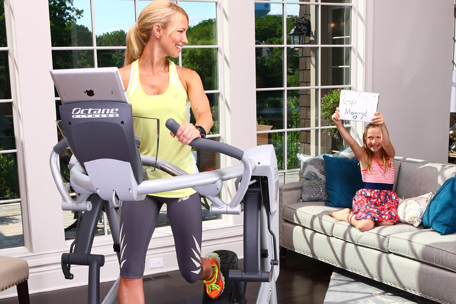Woman wearing yellow tank top and gray leggings on Octane Fitness ZR7 Zero Runner elliptical machine in bright room with wind