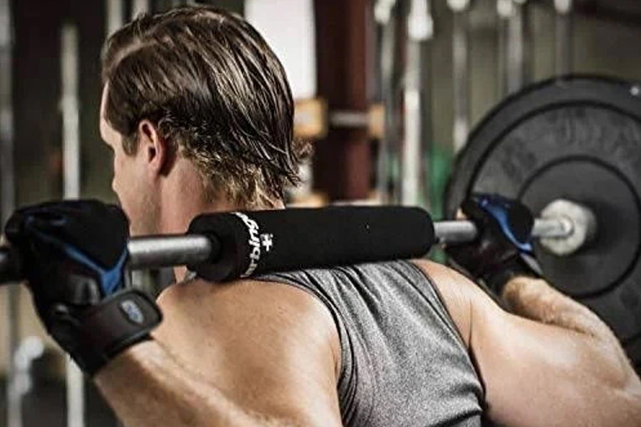 Black neoprene squat bar pad with silver branding worn by male model during weightlifting exercise