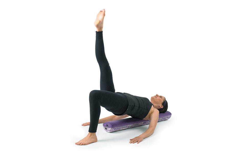 Woman lying on purple textured foam roller performing leg lift exercise on white background