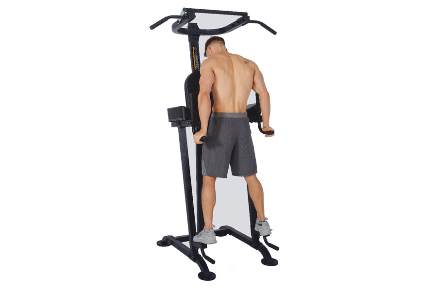 Black and gray vertical power tower with pull-up bar, dip station, and leg raise attachment, demonstrated by shirtless man we
