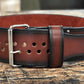 Brown leather power belt with metal stud details and silver buckle, flat lay on wood surface
