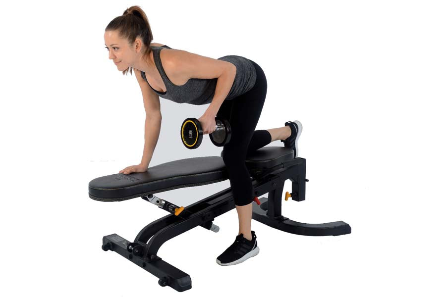 Woman performing dumbbell exercise on black adjustable weight bench with leg extension attachment