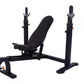 Black Olympic weight bench with adjustable backrest, leg extension, and dual squat racks on white background