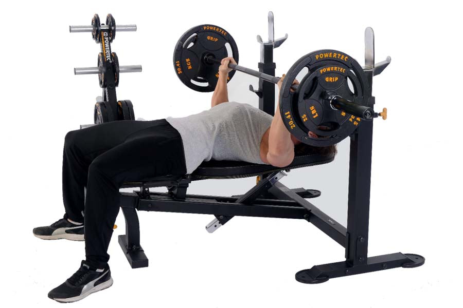Man performing bench press on black Powertec Olympic weight bench with orange and black weight plates