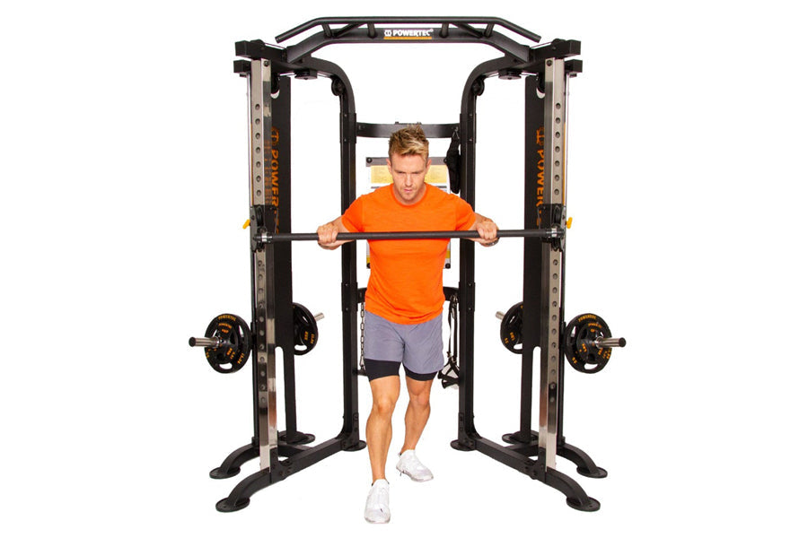 Black and silver functional trainer with dual cable stations and weight plates, demonstrated by man in orange shirt