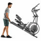 Man in gray shirt standing next to black and silver elliptical machine with digital display on white background
