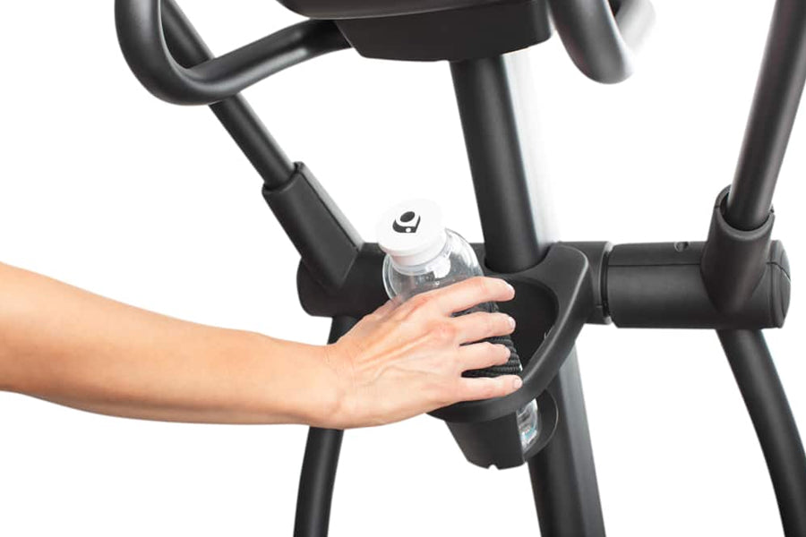 Black elliptical machine with integrated water bottle holder, worn by model on white background