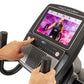 ProForm Carbon HIIT H10 elliptical with touchscreen display showing workout video, black frame with handlebars, user's hands 