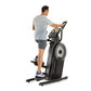 Man exercising on black ProForm elliptical with digital display, white flywheel, and handlebar grips against white background