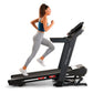 Woman running on black ProForm Carbon TLX treadmill, wearing blue sports bra and gray leggings, on white background