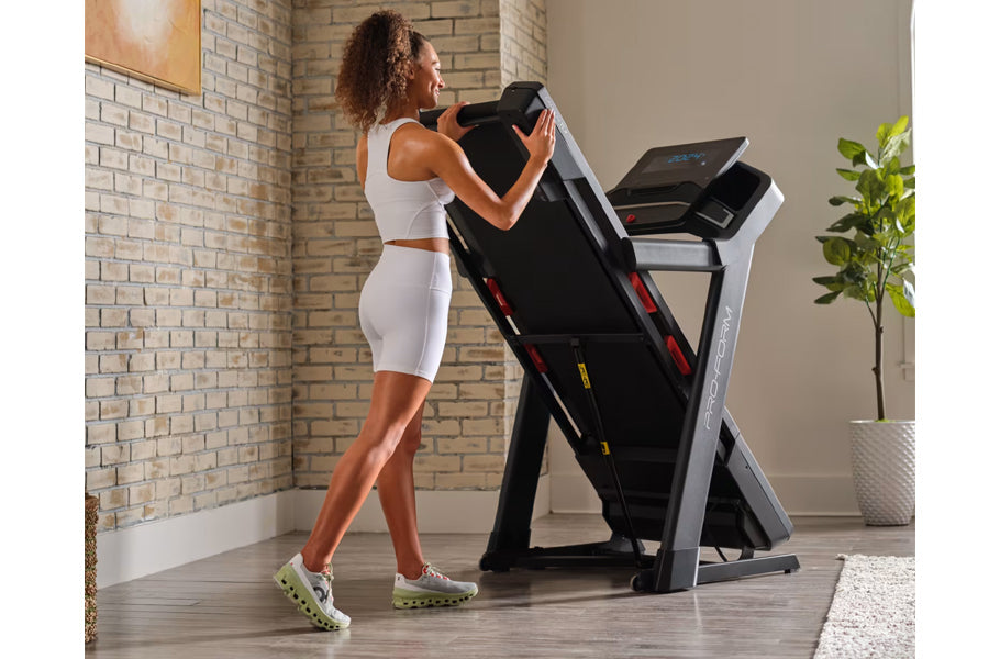 Woman in white crop top and shorts using black and silver ProForm treadmill in home gym with brick wall