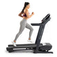 Woman running on black ProForm Carbon TL treadmill, wearing purple sports bra and gray leggings