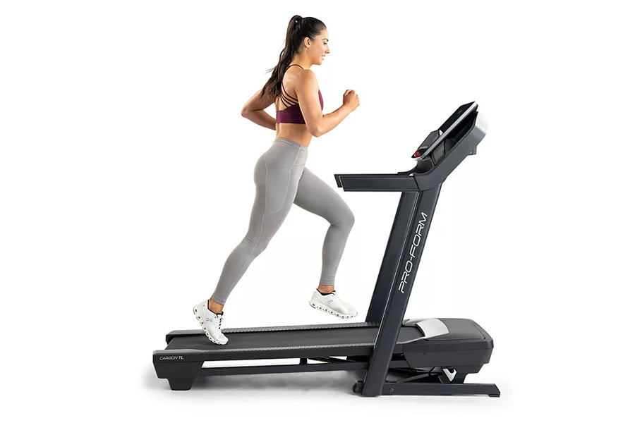 Woman running on black ProForm Carbon TL treadmill, wearing purple sports bra and gray leggings