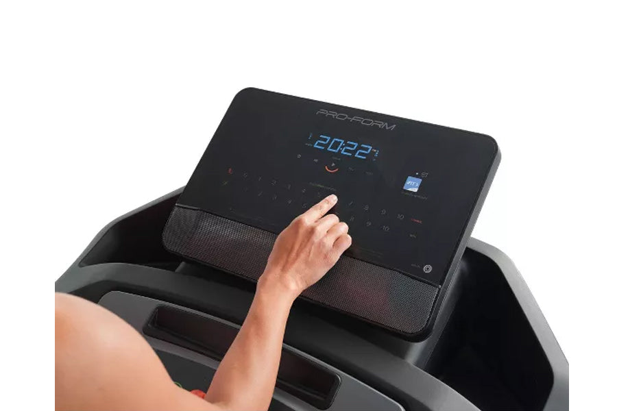 Hand touching control console of black ProForm treadmill with blue digital display showing speed, worn by model on white back