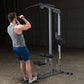Man using silver and black lat pulldown machine in gym setting, demonstrating pull-down exercise position