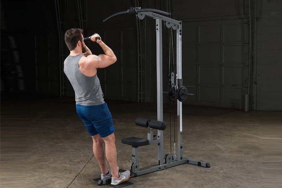 Man using silver and black lat pulldown machine in gym setting, demonstrating pull-down exercise position