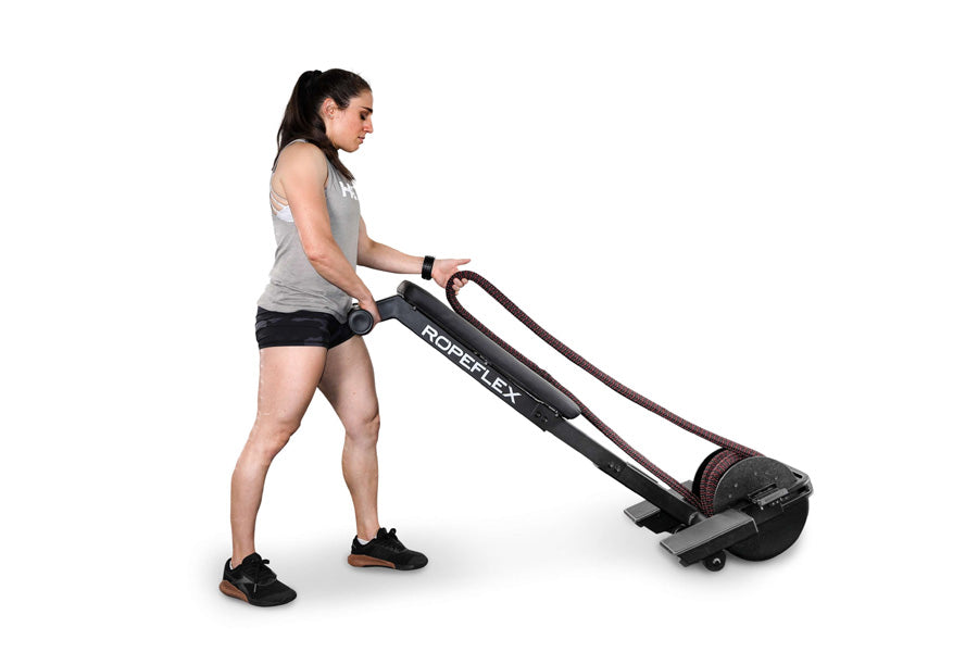Woman using black Ropeflex RX2200 horizontal rope trainer with maroon accents on white background