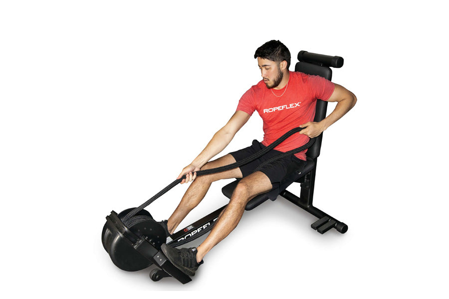 Man wearing red Ropoflex t-shirt using black Ropeflex RX2300 rope trainer machine with adjustable seat on white background