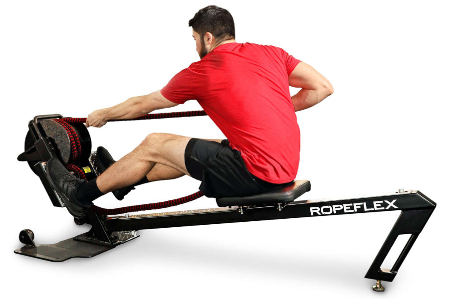 Man in red t-shirt and black shorts using black Ropeflex rowing machine with rope on white background
