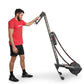 Man in red shirt and black shorts using black and gray rope rowing machine on white background