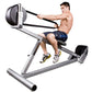Shirtless man using gray and black incline rope trainer with medicine ball attachment, demonstrating exercise form against wh