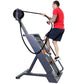 Man in red shirt and navy shorts using black and gray rope climbing machine with resistance wheel against white background