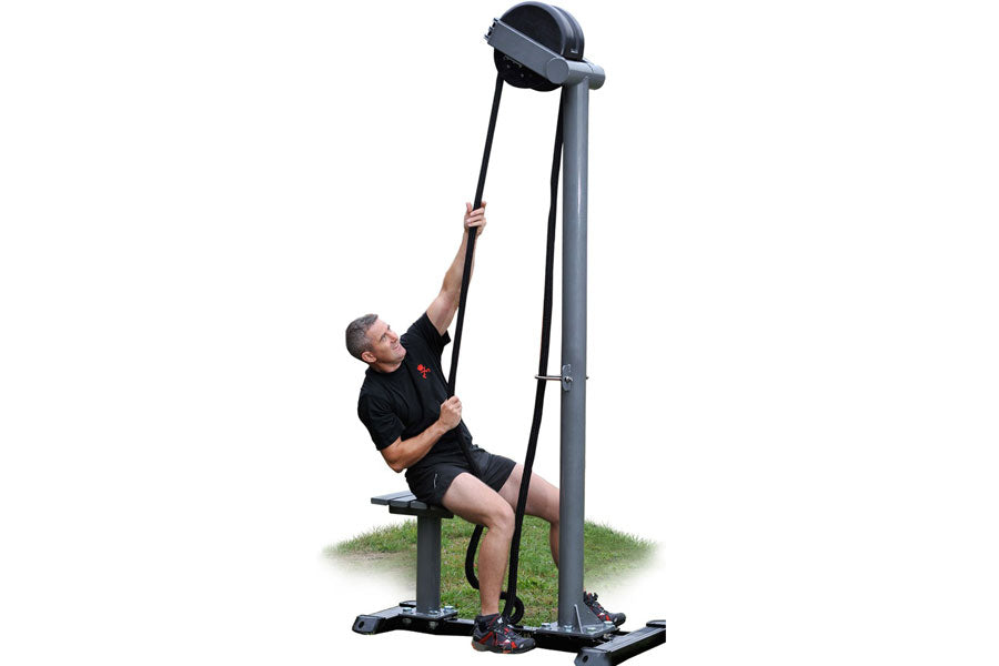 Man using black Ropeflex RX5500 rope trainer machine with tall vertical frame and pulley system on grass