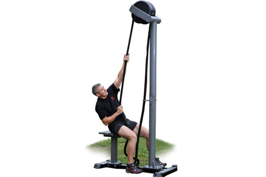Man using black Ropeflex RX5500 rope trainer machine with tall vertical frame and pulley system on grass