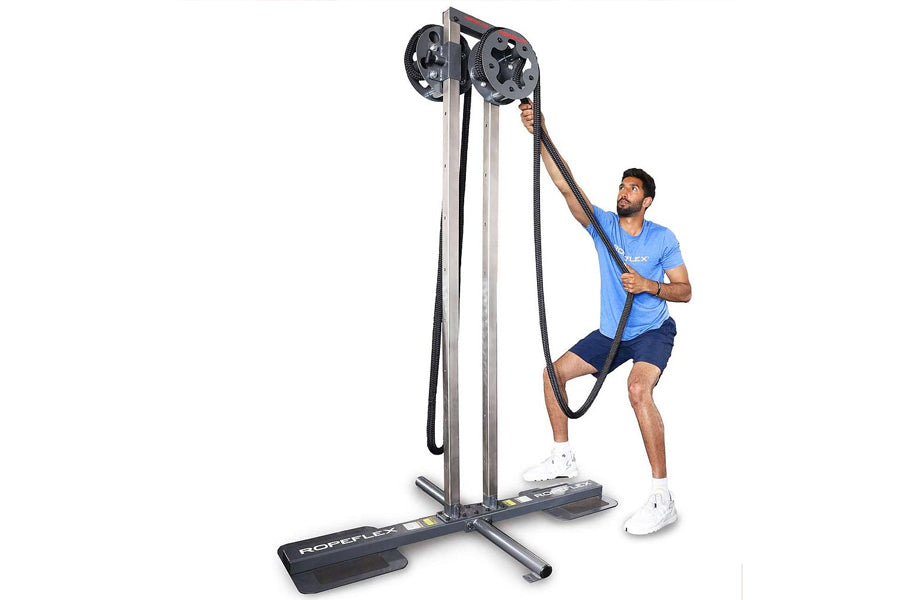 Man in blue shirt using tall gray and black rope trainer with dual pulleys on white background