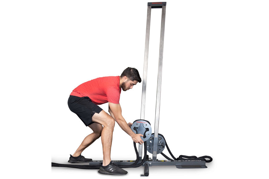 Man in red shirt using Ropeflex RX1500 upright rope trainer with tall metal frame on white background