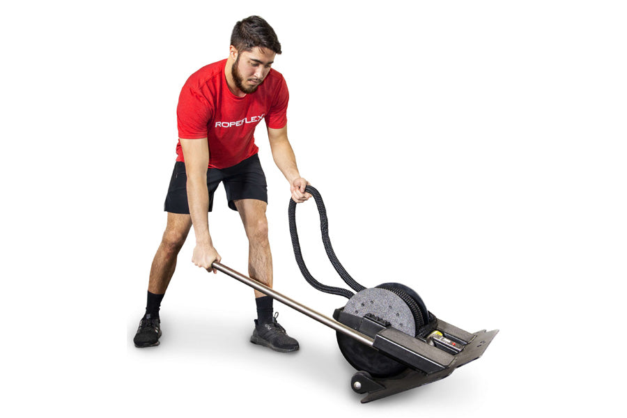Man wearing red Ropeflex t-shirt and black shorts using compact rope trainer with black handles on white background
