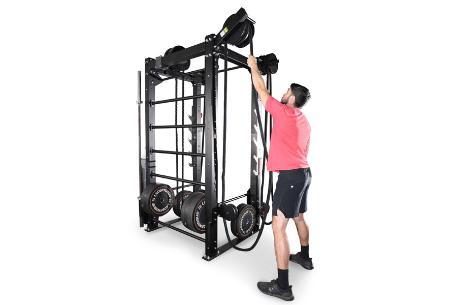Man in pink shirt using black steel cable machine with weight plates, shown on white background