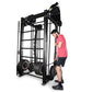 Black steel Smith machine with rope trainer attachment, model man in pink shirt demonstrating use on white background