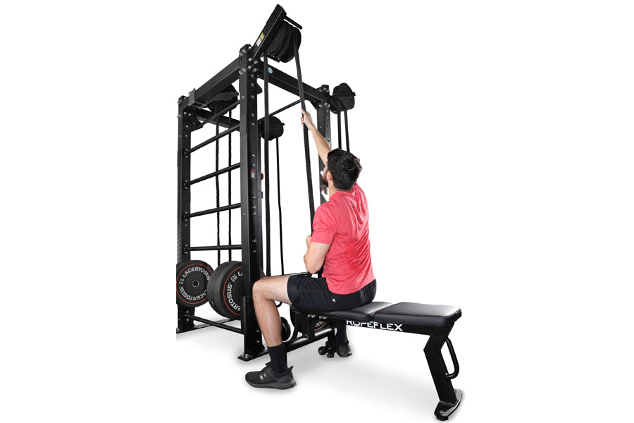 Man in red shirt using black Ropeflex RX2100 rope trainer machine with attached bench on white background
