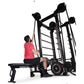 Man wearing pink shirt using RopeFlex RX2100 black rope trainer machine with bench seat on white background