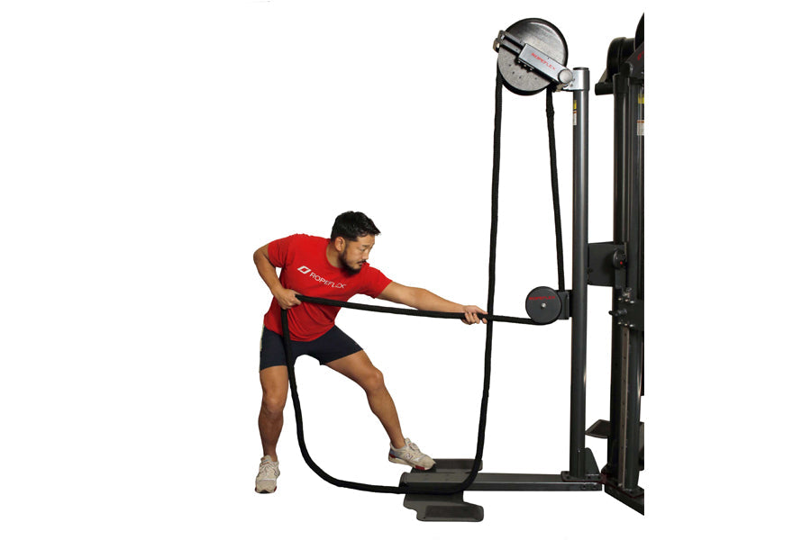 Man in red shirt using black Ropeflex rope trainer machine with circular weight indicator and rope attachment on white backgr