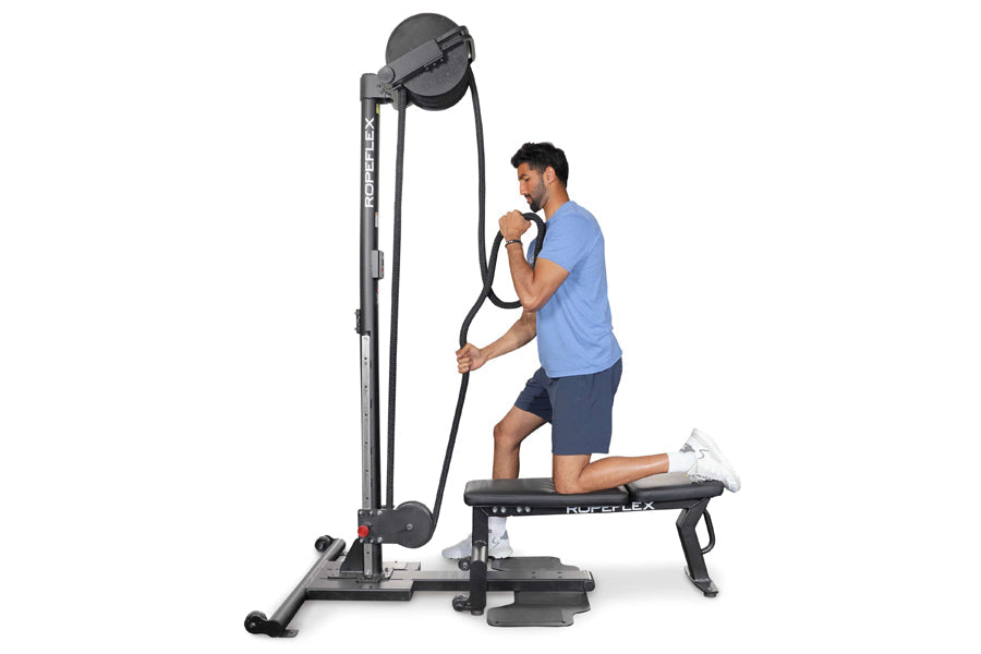 Man in blue shirt using Ropeflex RX2500 upright rope trainer with black frame and bench on white background