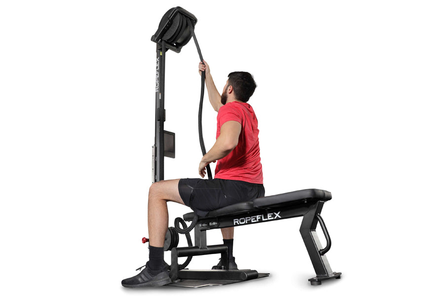 Man in red shirt using black Ropeflex RX2500 upright rope trainer with overhead pulley system on white background