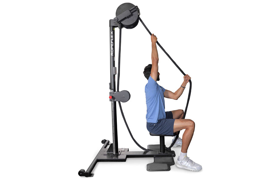 Man using black Ropeflex RX2500 upright rope trainer with pulley system, wearing blue shirt and navy shorts