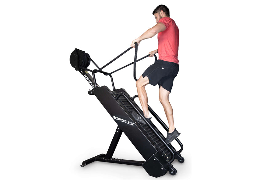 Man in pink t-shirt and black shorts using black Ropeflex RX4400 rope climbing machine against white background