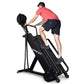 Man in coral t-shirt and black shorts using black Ropeflex RX4400 rope climbing machine against white background