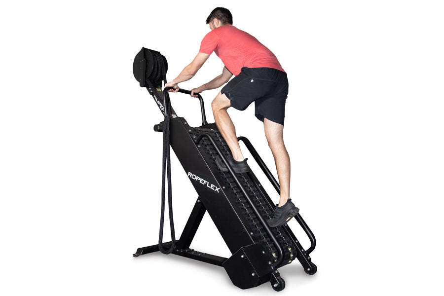 Man in coral t-shirt and black shorts using black Ropeflex RX4400 rope climbing machine against white background