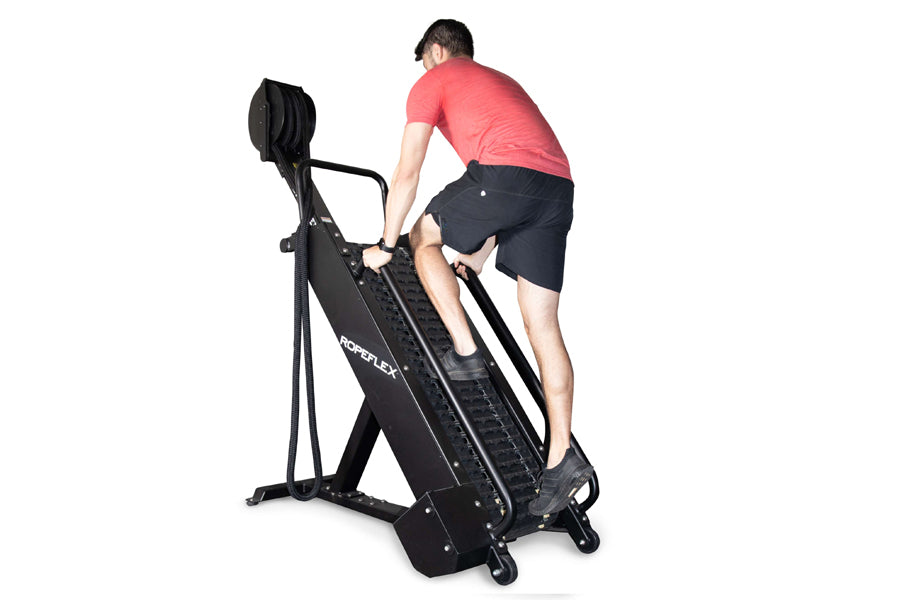 Man in coral t-shirt and black shorts using black Ropeflex RX4400 rope climbing machine on white background