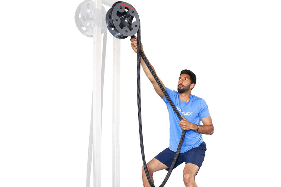 Man in blue shirt using black rope drum attachment mounted on white pole for training exercise